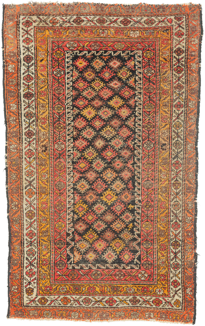 This Kurdish rug was handwoven during the middle of the 20th century.

It features an all-over design of latch hooked diamonds that sparkle against a deep brown/ almost black ground. Framed by a series of border in an uncommon palette of yellows, oranges, pinks and ivory.