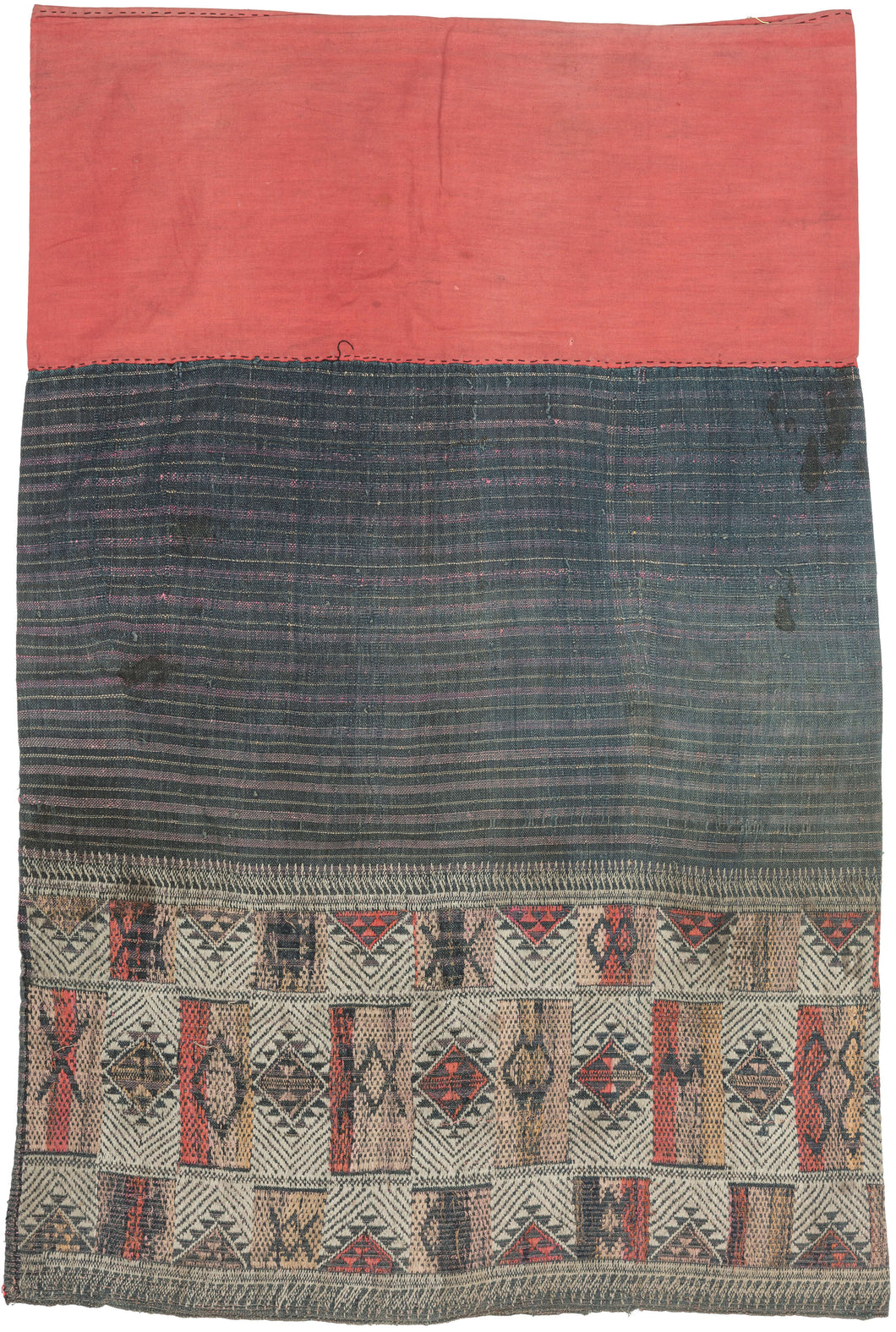 A finely woven woman’s skirt associated with Tai-speaking communities of northern Laos and northwestern Vietnam.

The textile is constructed in three distinct sections with a red cotton waistband, a dark indigo body enlivened with subtle horizontal striping, and an intricately patterned lower panel. The restrained palette of indigo, cream, ochre and red gives the skirt an unusually graphic quality.