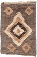 A wonderfully tactile Angora Tulu rug distinguished by its exceptionally soft, shaggy pile and striking geometric composition. Woven in a restrained palette of undyed Angora goat hair, the rug features a rich, earthy field of charcoal brown and warm taupe, punctuated by an ivory central medallion with jagged, irregular contours.