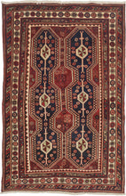 A Richly colored tribal rug with a striking double-column format of two tall elongated medallions&nbsp;on a deep indigo ground, each structured around a vertical spine of diamond forms quartered in olive and cream. The m&nbsp;red field between and around them reads almost as a third element, giving the composition an unusual density. Colors throughout are well-preserved with navy, red, ivory, and a muted green that surfaces in the medallion interiors and guard borders.