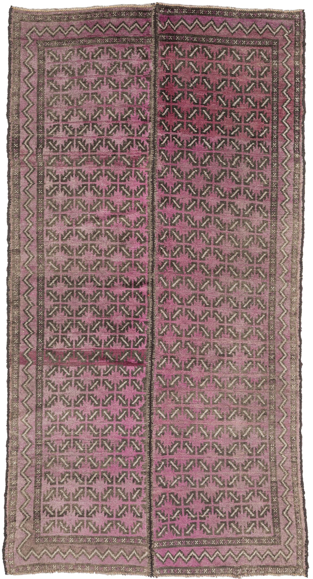 A distinctive Baluch rug featuring an allover lattice of small, repeating arrow and hooked motifs arranged in a tight, rhythmic grid. The rug is constructed in two&nbsp;joined panels and the&nbsp;pattern has a strong directional energy that creates movement across the surface while maintaining a disciplined geometric structure.