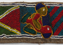 A striking Yoruba beaded sash from Nigeria, densely worked with glass beads in bold red, blue, green, yellow, white, and black. The long narrow form is divided into geometric panels with diagonal bands, diamond motifs, and a dramatic raised mask-like face at one end.