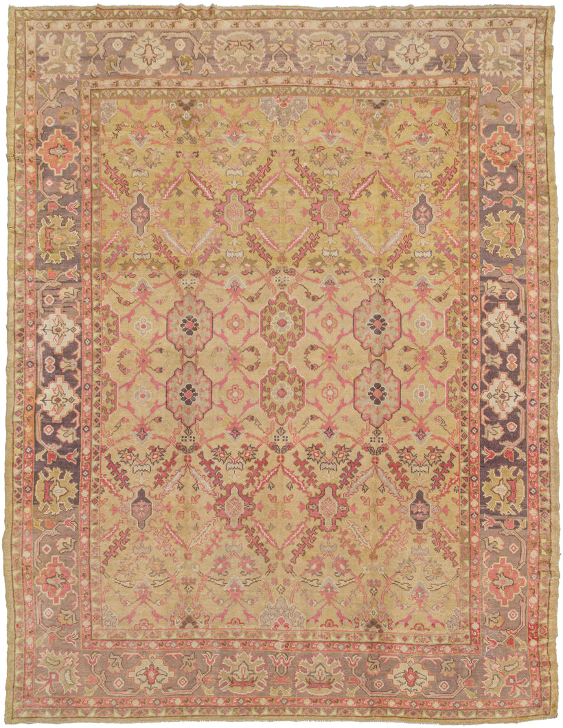 Antique Anatolian Oushak featuring an all-over design which is a combination of multiple lattice designs. A rare combination of bright pink, coral, soft olive, lilac, and lavender on a pale yellow ground gives this piece intrigue and calming energy. Perfectly framed by a palmette border that shifts from lavender to lilac with natural fading. A unique piece that is both collectible and highly decorative.