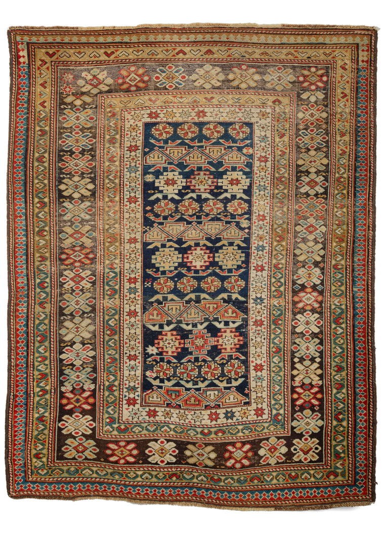 Antique Caucasian Chi Chi scatter rug featuring classic chi chi patterning of hooked polygons, rosettes, and alternating arrows in soft blues, yellows and reds on an inky blue field. The main border features characteristic bursting rosettes on a lovingly oxidized brown. An abrashed laleh abbassi gaurds the perimeter of the rug. 