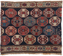 Antique NW Persian Shahsavan Mafresh fragment featuring a field of well-staggered octagons that float above a midnight blue ground. Each octagon is filled with a latch-hooked protection device in a spectacular range of contrasting but balanced tones of red, green, pink, purple, and blue. It is neatly framed on the top and bottom by thin and tight "S" cartouche borders.