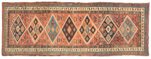 This Antique NW Persian Runner features large diamonds in orange, brown, light, and dark blue on a brick ground. Each diamond is filled with five further diamonds "dice five" formation. Botehs can also be found both inside and outside of the diamonds on the field along with blossoming flowers and other shapes. The whole is framed by three thin borders- a small scale "dice five", a scrolling vine, and finally a red and blue laleh abbasi guard border.