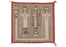 Navajo Yei tapestry featuring three “Yei” or holy people on a natural grey background and framed by a red border. The first two smaller figures are woven holding arrows (potentially). The third figure is a rainbow guardian, whose body surrounds the figures on three sides, as a form of protection. All the figures are female as women are traditionally rendered with square heads.