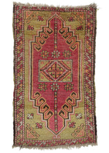 Turkish Yastik rug features a latch-hooked purplish pink field which offers a pleasing contrast with the pistachio center and cornices. Chocolate, ivory and creamsicle provide lively accents. The whole is framed by a border of tightly interlocking "z" shapes that alternate in each featured tone. 