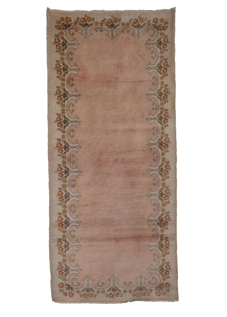 Chinese Khotan rug, handwoven during the 1980s in NW China. It features a plain soft pink field with a scalloped border. In very good condition, signs of wear consistent with age.