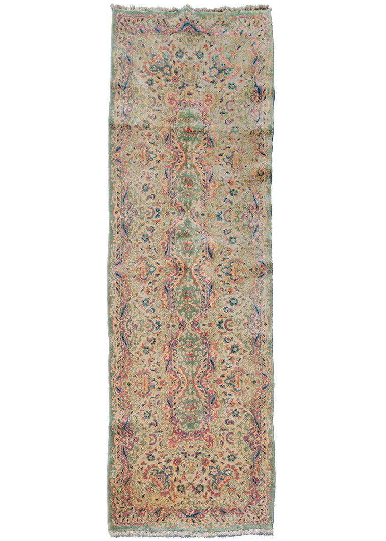 Kerman fragment runner that features a flowing, floral design with scrolls and other baroque elements associated with French Savonnerie rugs.  Bright raspberry pink, light blues, gold and creams on a pistachio ground.