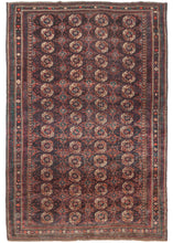 Large Afghan Turkmen purple toned rug featuring a traditional Tekke gül design with both burnt and bright orange, ivory, and green accents on a soft multi-shade aubergine ground. A precursor to the "Bokhara" rugs that would be woven by Afghan refugees in Pakistan at the end of the 20th century.