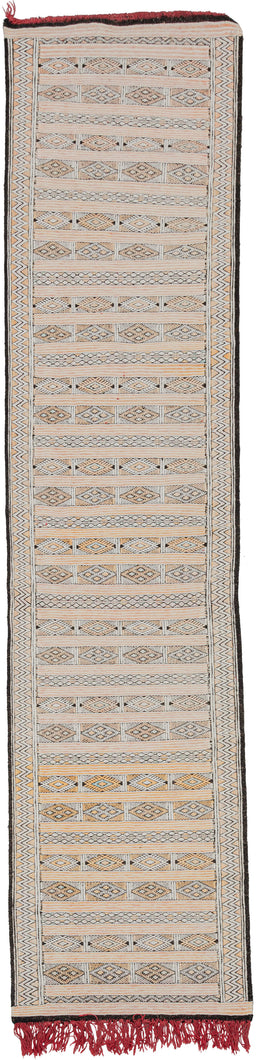 Midcentury Hanbel runner featuring crafted of cotton wefts on a cotton foundation and features subtle details in silk throughout. Horizontal rows of many different geometric shapes span the length of the rug. Black, white, soft yellow, and dashes of light blue silk make up the palette with long red fringes providing a colorful detail.