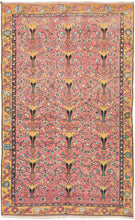 Floral vintage Anatolian Turkish pink & yellow rug featuring an all-over design of stylized vases surrounded by blossoming flowers and small birds in vibrant blues, greens ivory, and gold on a flamingo ground. Surrounded by a main border of rosettes and scrolling leaves on a golden yellow ground.
