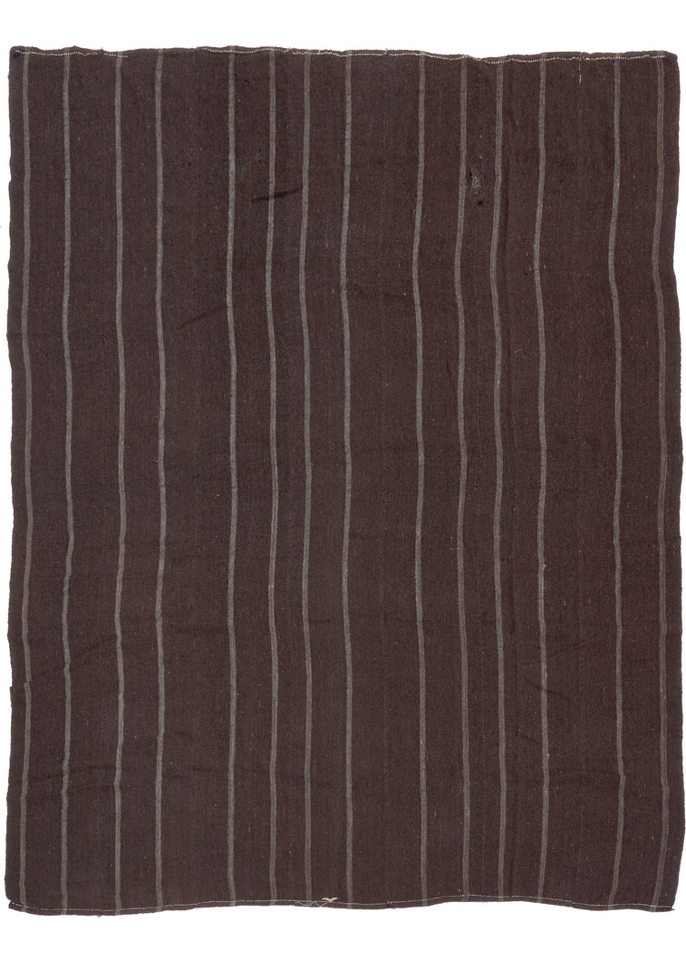 This Turkish Tent Kilim features thin chalky white stripes of cotton on an expansive dark brown ground composed of goat hair.  There is a central white stripe, followed by alternating black and orange stripes. These sturdy and hard-wearing goat hair kilims were woven in various strips and usually intended as tent rugs.