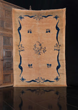 Chinese Deco rug, handwoven during the second quarter of the 20th century.   This elegant rug features a minimalist design composed of a dainty blossoms and ribbons woven in shades of indigo blue on a soft beige field. A very subtle green-beige border frames the rug and adds to the limited color palette.    In good condition, signs of wear consistent with age. Low pile, with a soft handle.