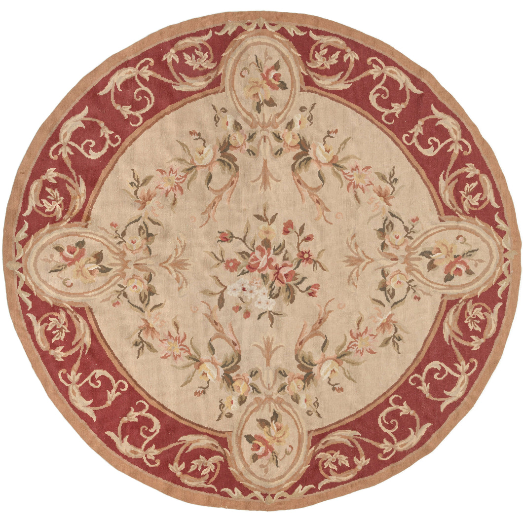 This Round Aubusson Style Needlepoint was designed in classic French Aubusson style. It features a central bouquet on a beige ground surrounded by a wreath of blossoming florals with four oval cameos that scallop into the maroon rinceau border.